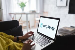 Image of laptop on a person's lap with the Perplexity logo on the screen